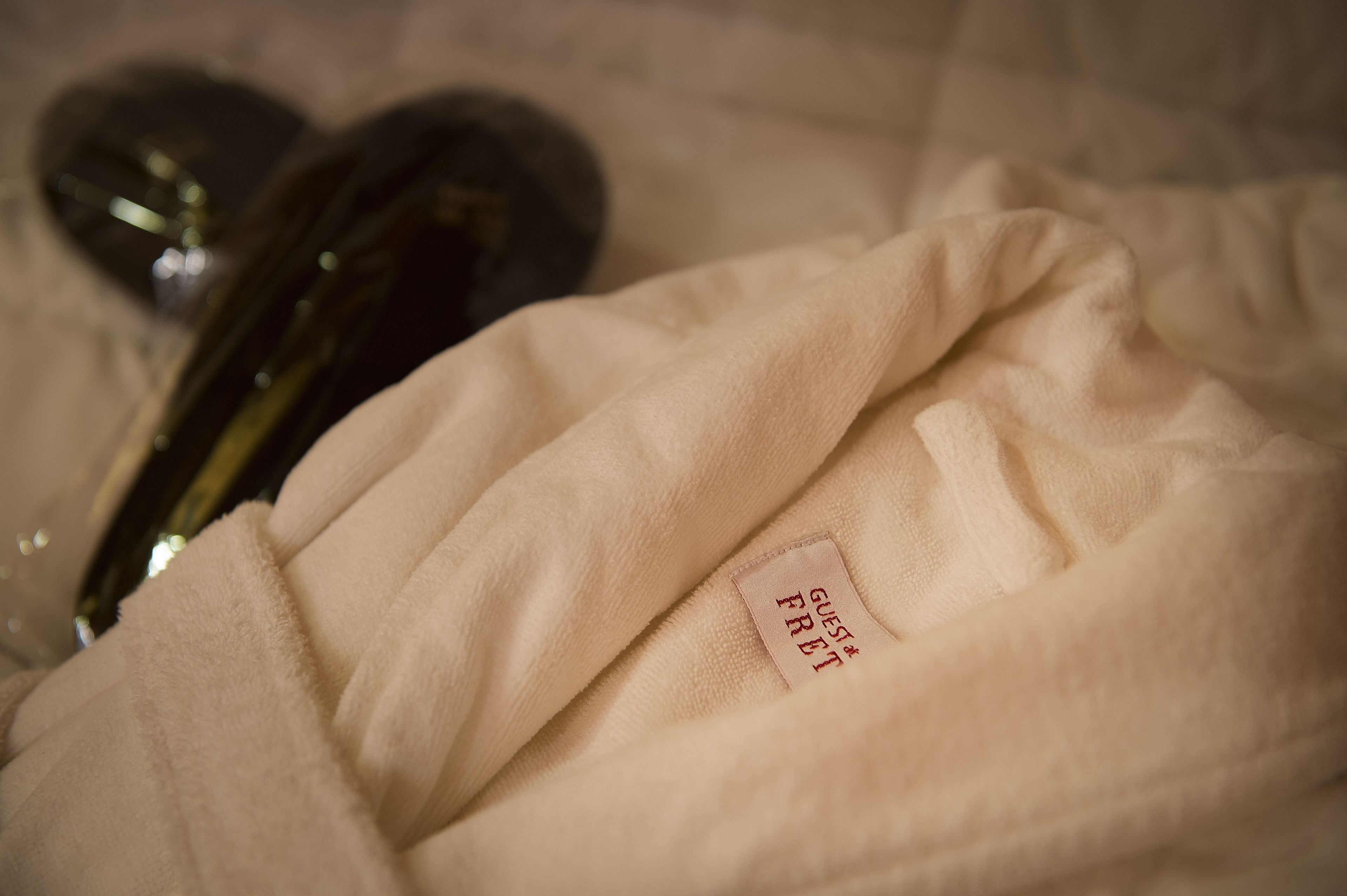 A close-up of a beige fabric item with a tag reading "GUEST FRET".