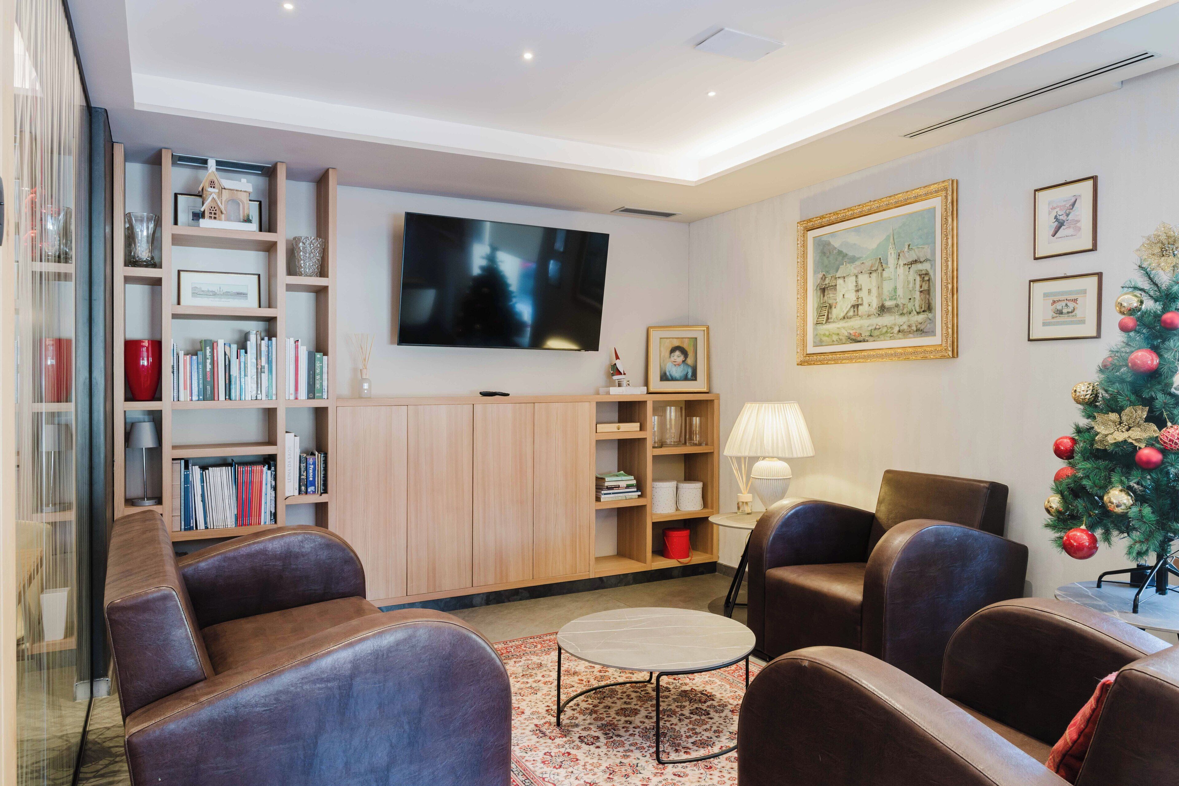 Ein modernes Wohnzimmer mit Ledersofas, einem Flachbildfernseher, einem Bücherregal und einem Weihnachtsbaum.