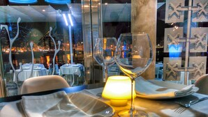 Mesa preparada para comer con vista a un paisaje urbano nocturno.