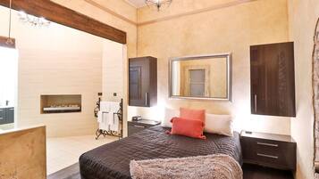 A bedroom with a large bed, a mirror, dark wooden cabinets, and a small window.