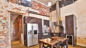 Una cocina con pared de ladrillo, electrodomésticos de acero inoxidable y una mesa de comedor de madera.