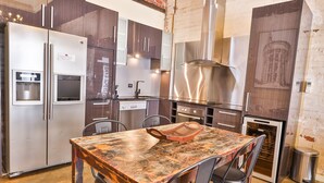 Una cocina moderna con electrodomésticos de acero inoxidable, una mesa de madera y una pared de ladrillo.