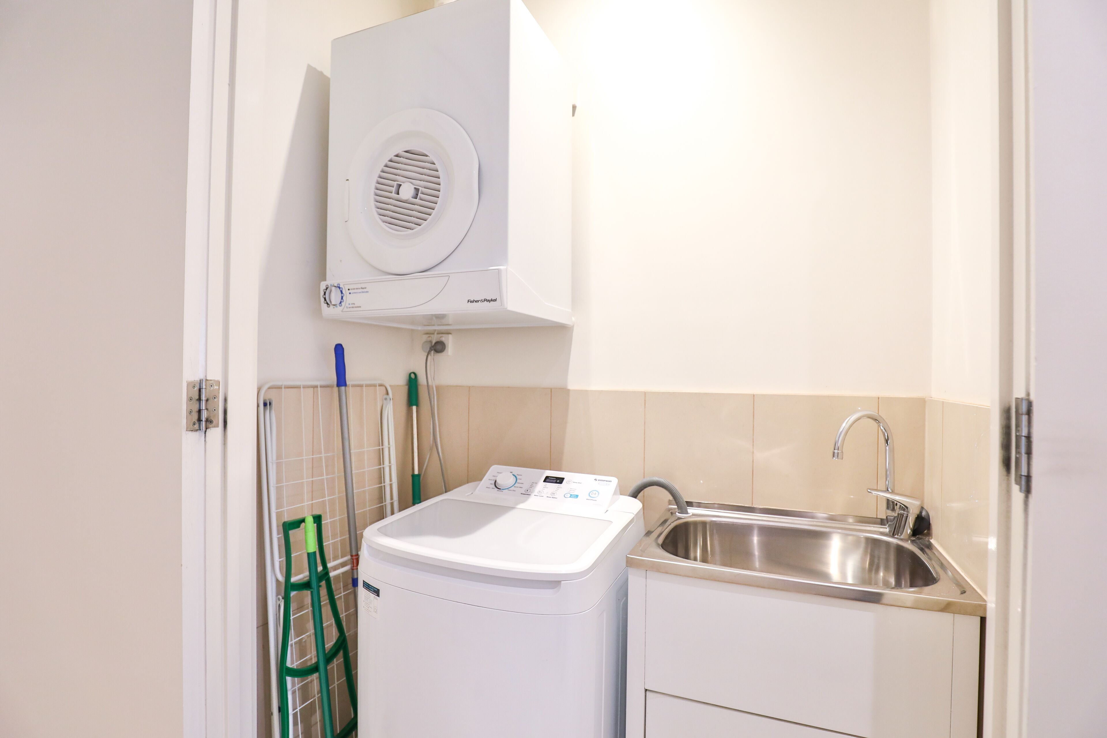 A compact kitchen with a washing machine, a sink, and a small cabinet.