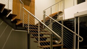 Una escalera moderna con barandillas de metal y peldaños de madera, que conduce a un piso superior.