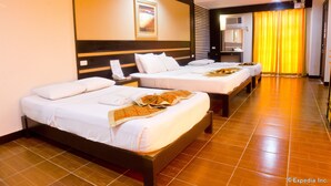 Habitación de hotel con dos camas, un espejo grande, un equipo de aire acondicionado y una cortina amarilla.