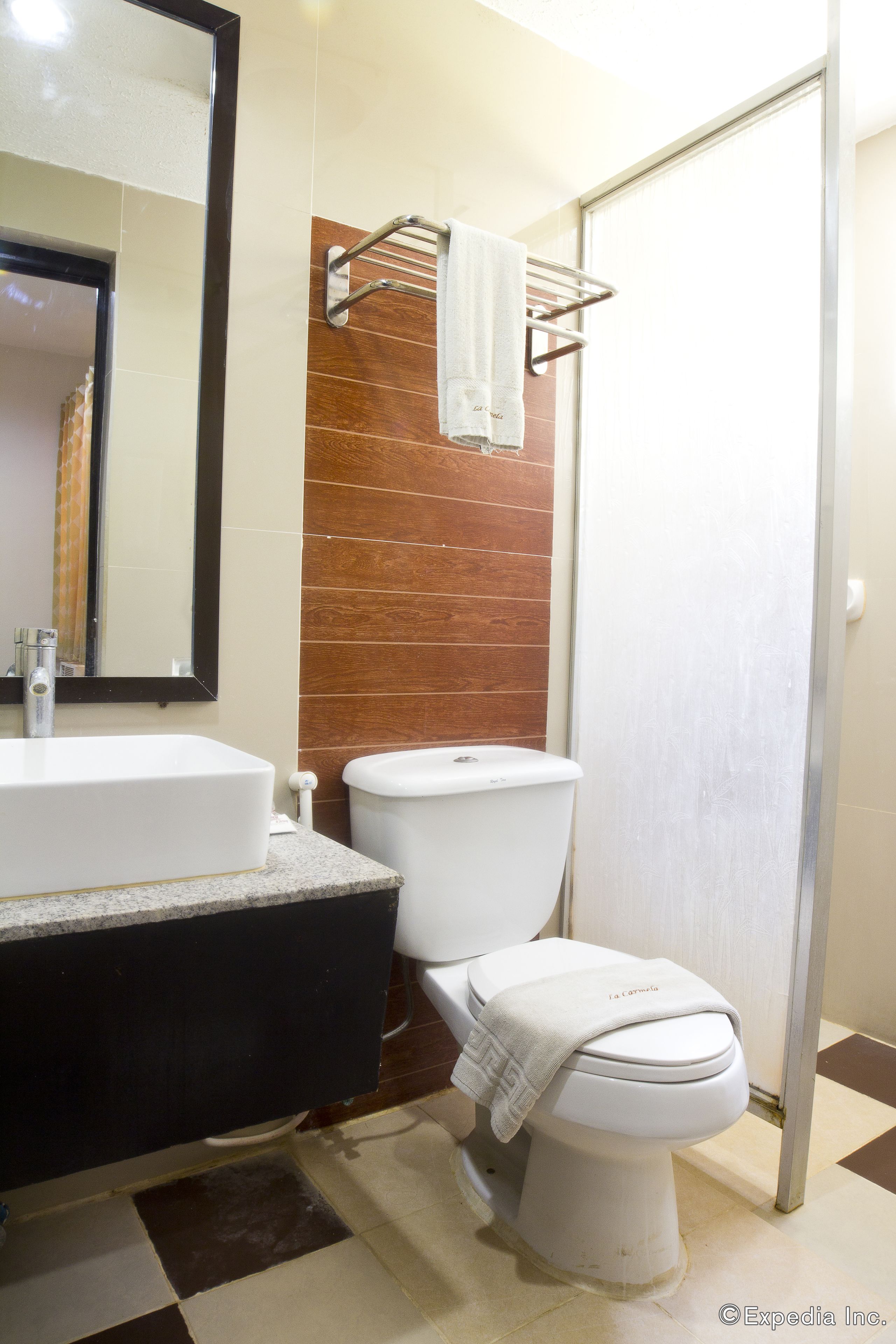 Un baño con lavamanos blanco, inodoro y perchero para toallas.