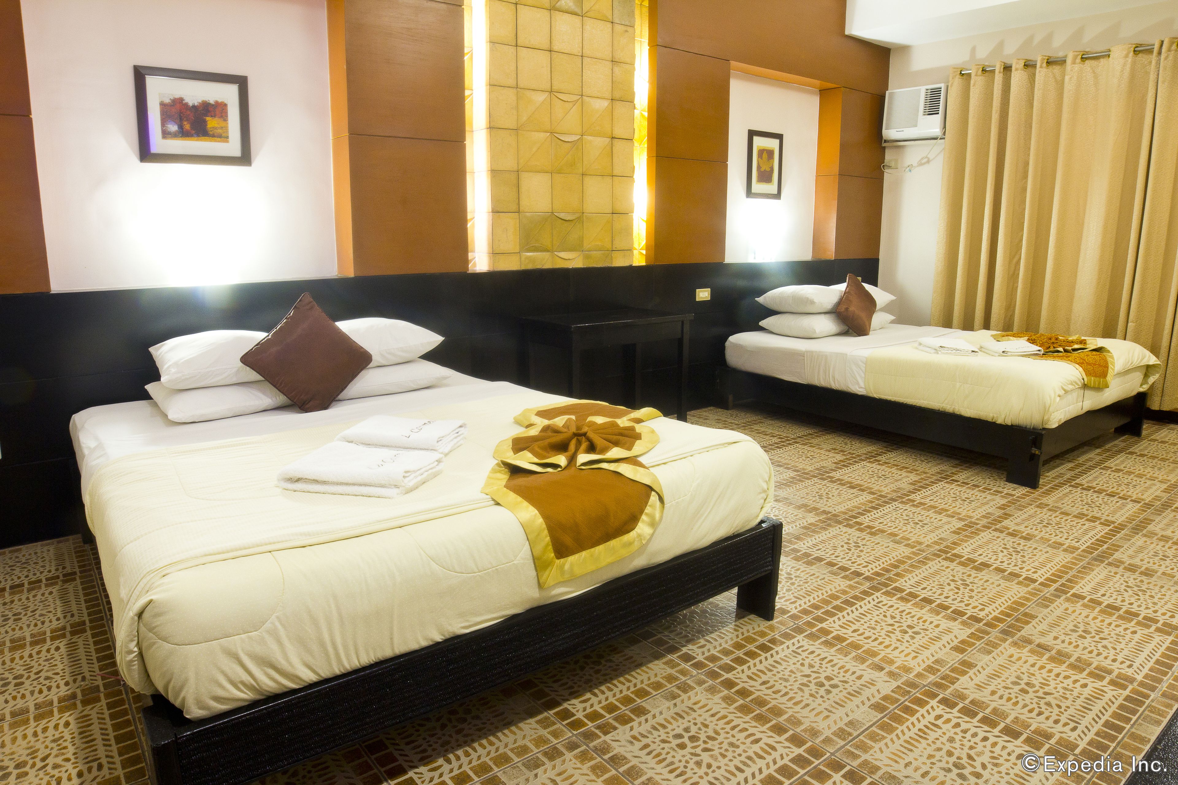 Een hotelkamer met twee bedden, een kleine tafel en een wandairconditioner.