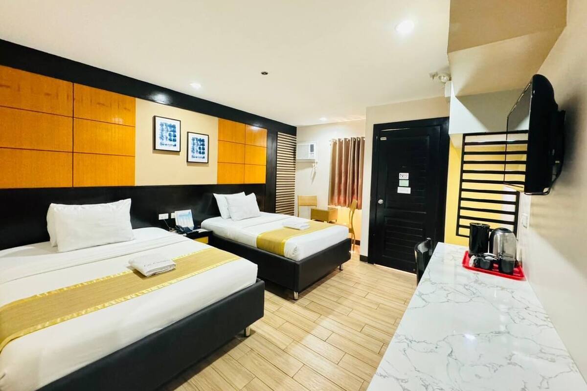 A hotel room with two beds, a marble-topped desk, a TV, and a wardrobe.