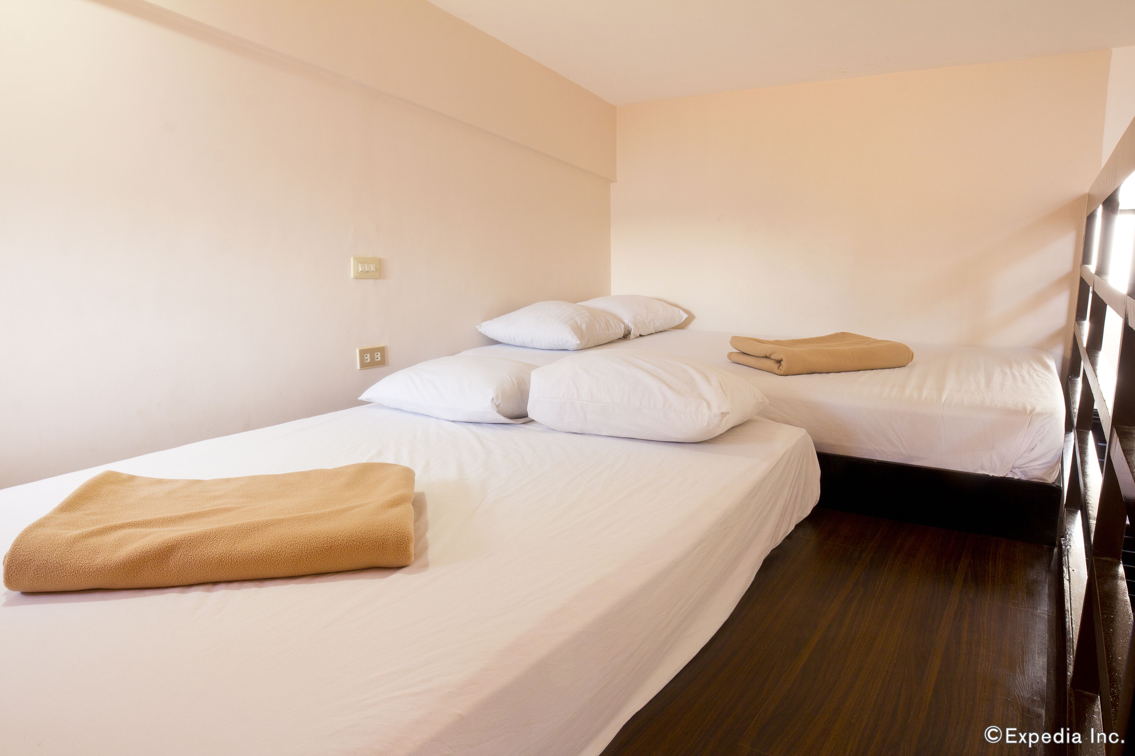 A hotel room with two beds, white bedding, and a wooden floor.