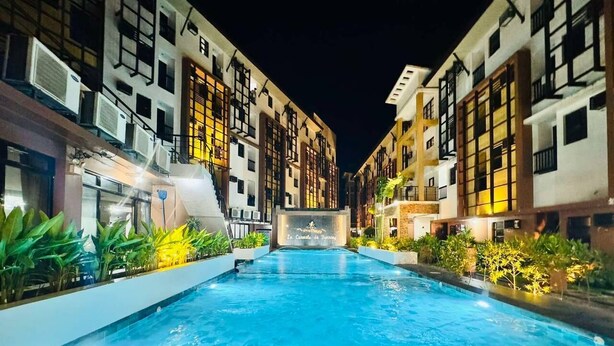 Una piscina rodeada de edificios de varios pisos con balcones y unidades de aire acondicionado.