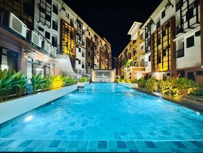 A swimming pool surrounded by multi-story buildings with balconies and air conditioning units. - La Carmela De Boracay Resort Hotel (Boracay Island)