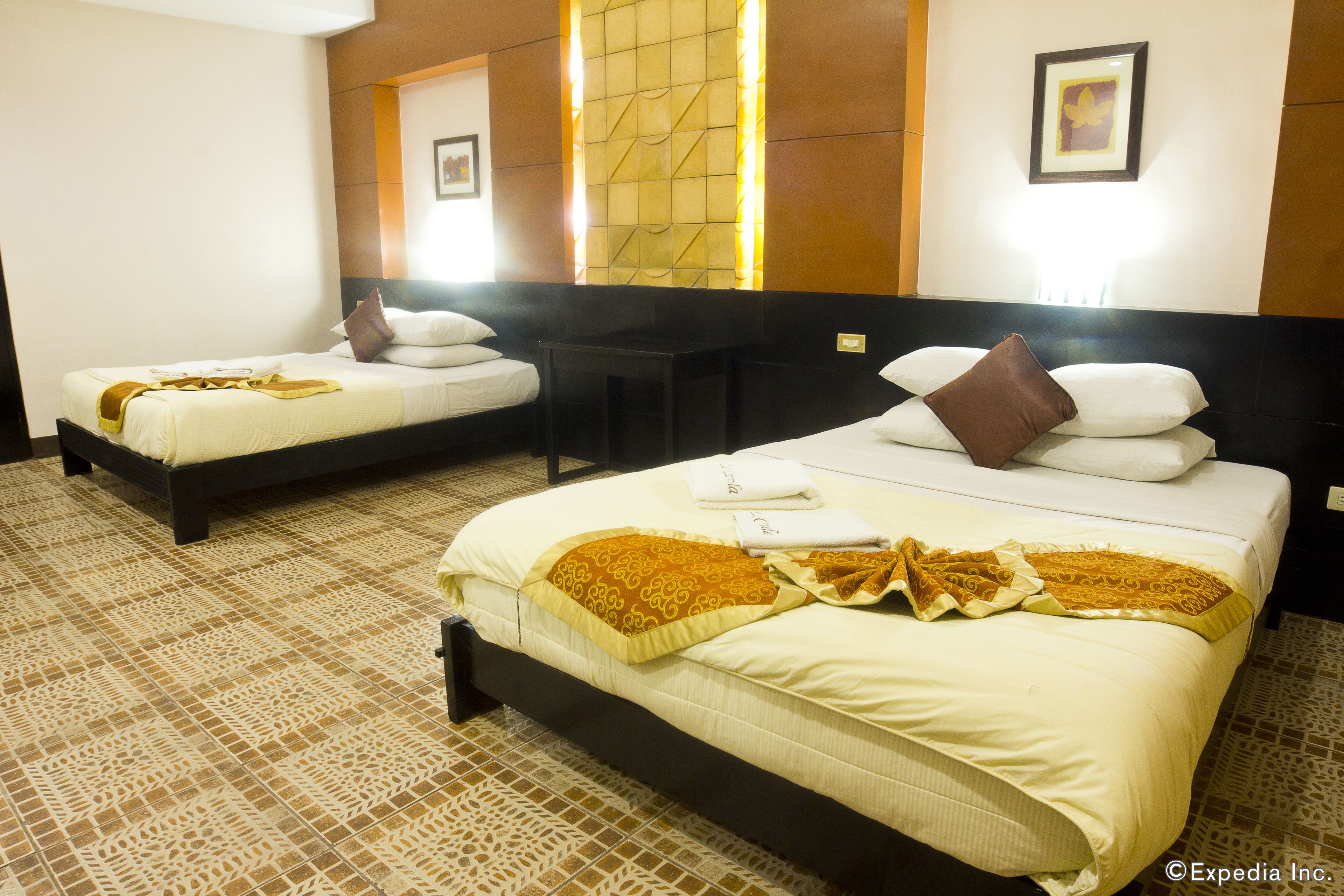 A hotel room with two beds, a small table, and a decorative wall panel.