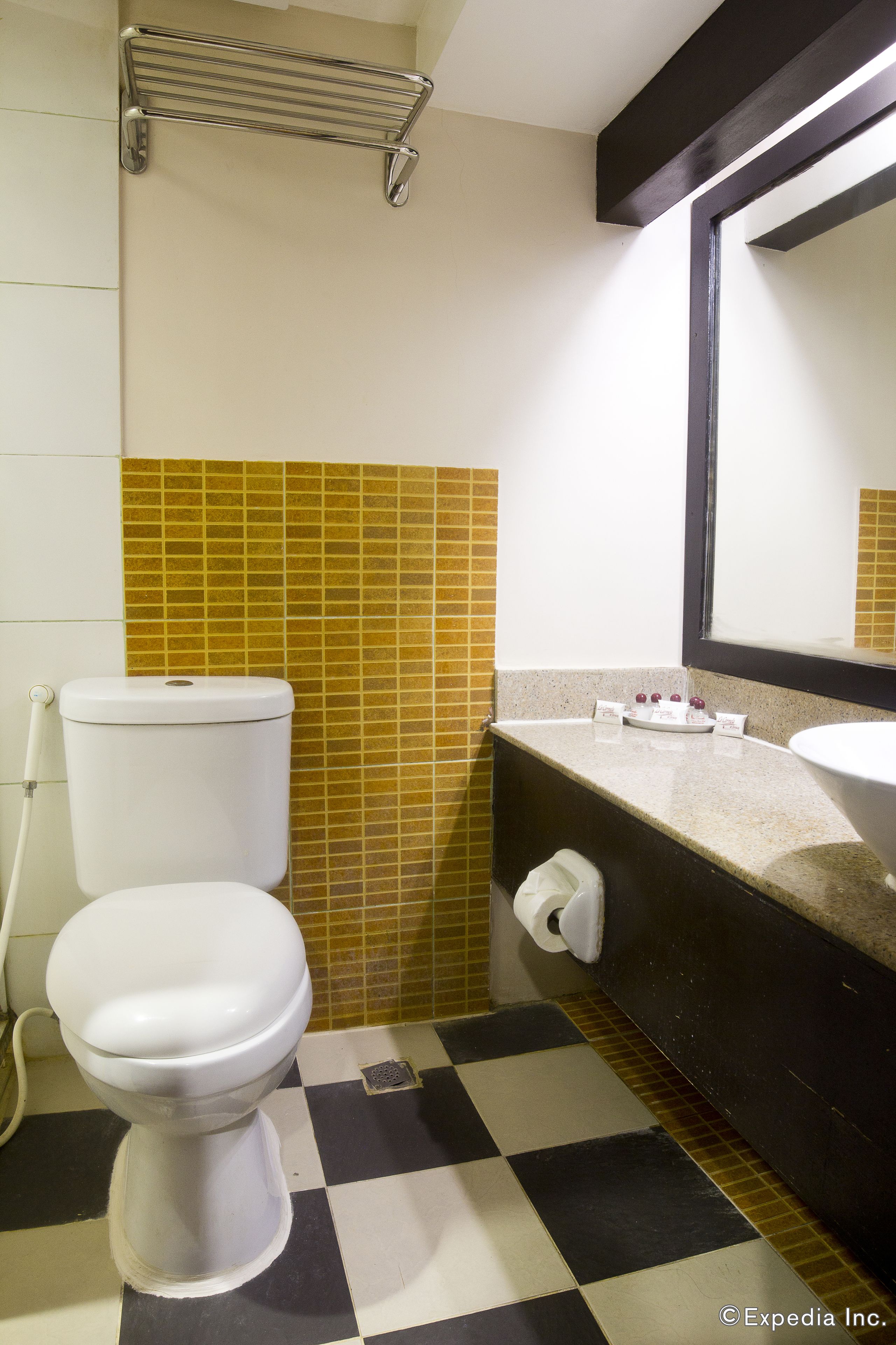 Et lille badeværelse med toilet, vask og spejl.