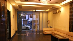 A hotel lobby with a sofa, a coffee table, a ceiling fan, and an air conditioning unit.