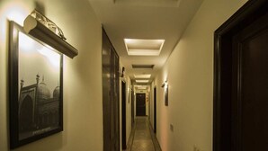 A hotel hallway with a framed picture of a building, recessed lighting, and doors on both sides.