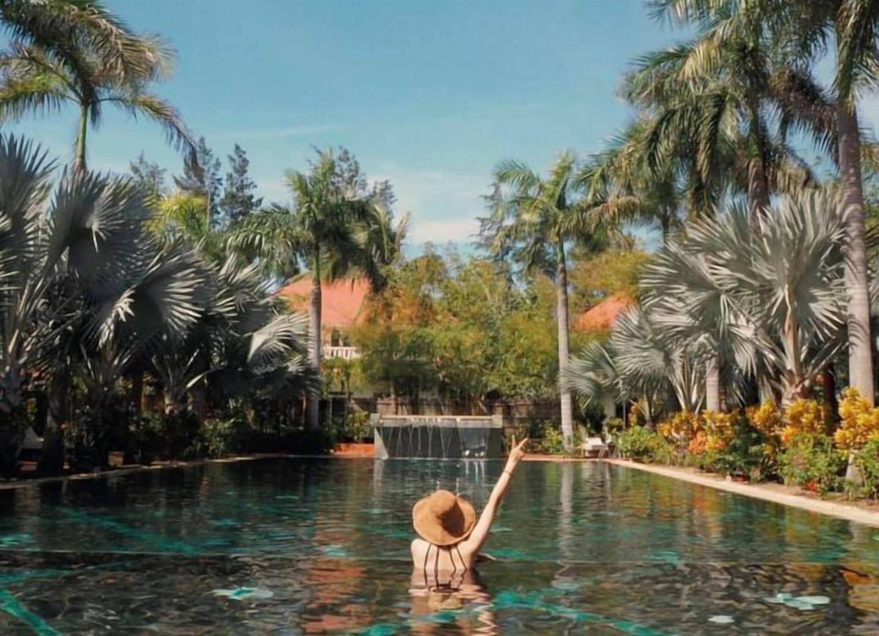A pool area with palm trees and a waterfall feature.