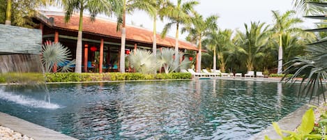 Una piscina al aire libre, sombrillas, sillones reclinables de piscina