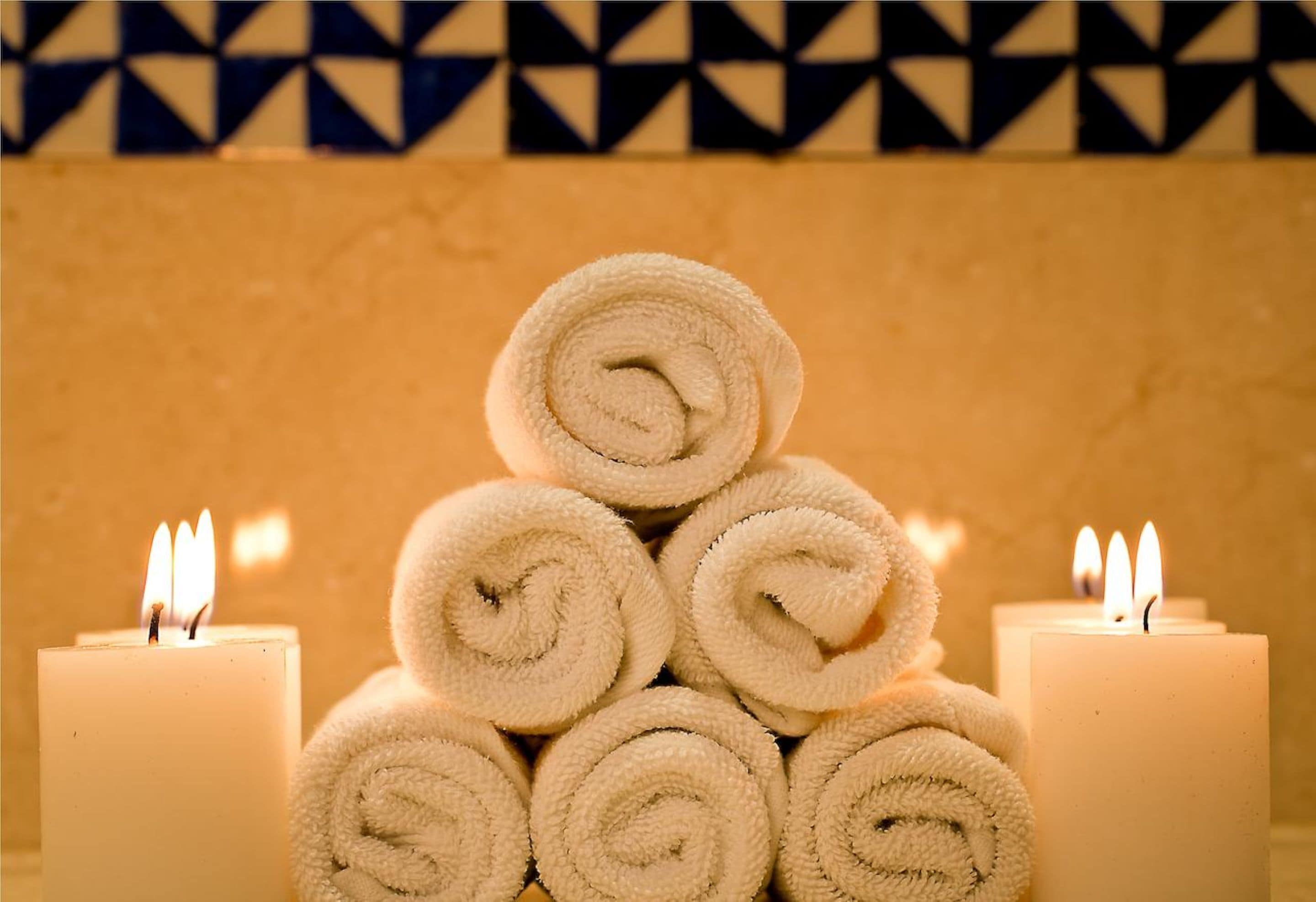 A stack of rolled towels with lit candles on either side.