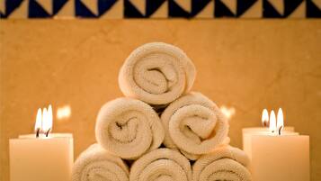 A stack of rolled towels with lit candles on either side.