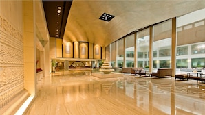 A spacious lobby with a polished marble floor, a reception desk, seating area, and large windows offering views of the city. - The LaLiT Jaipur (Jaipur)
