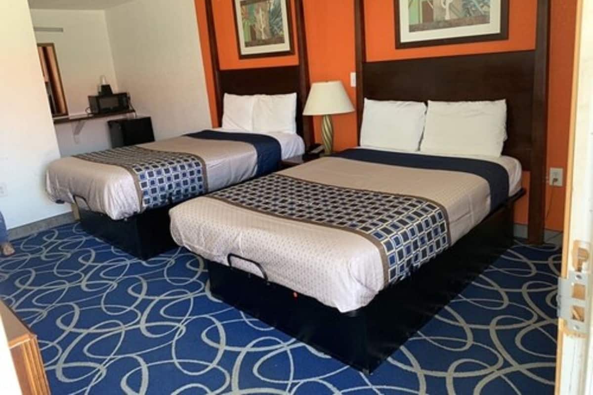 Habitación de hotel con dos camas, alfombra azul estampada y obras de arte enmarcadas en las paredes.