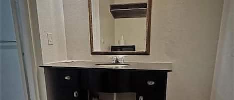 Un baño con lavabo, espejo y armario.