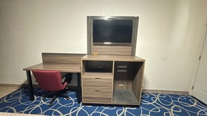 Une petite pièce comprenant un bureau, une chaise et un téléviseur.