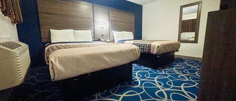 A hotel room with two beds, a large headboard, a patterned carpet, and a mirror on the wall.