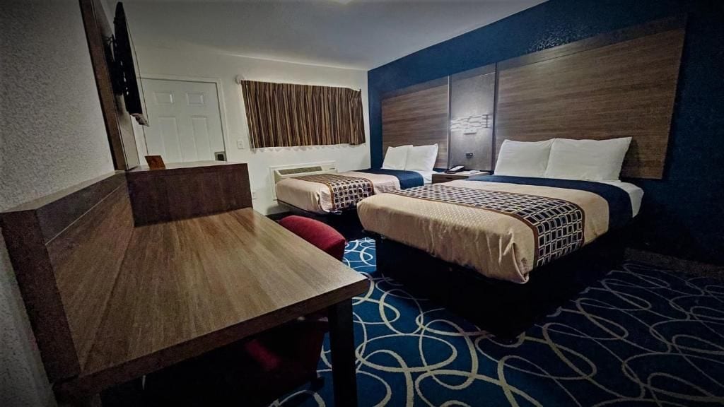 Una habitación de hotel con dos camas, un escritorio y una televisión.