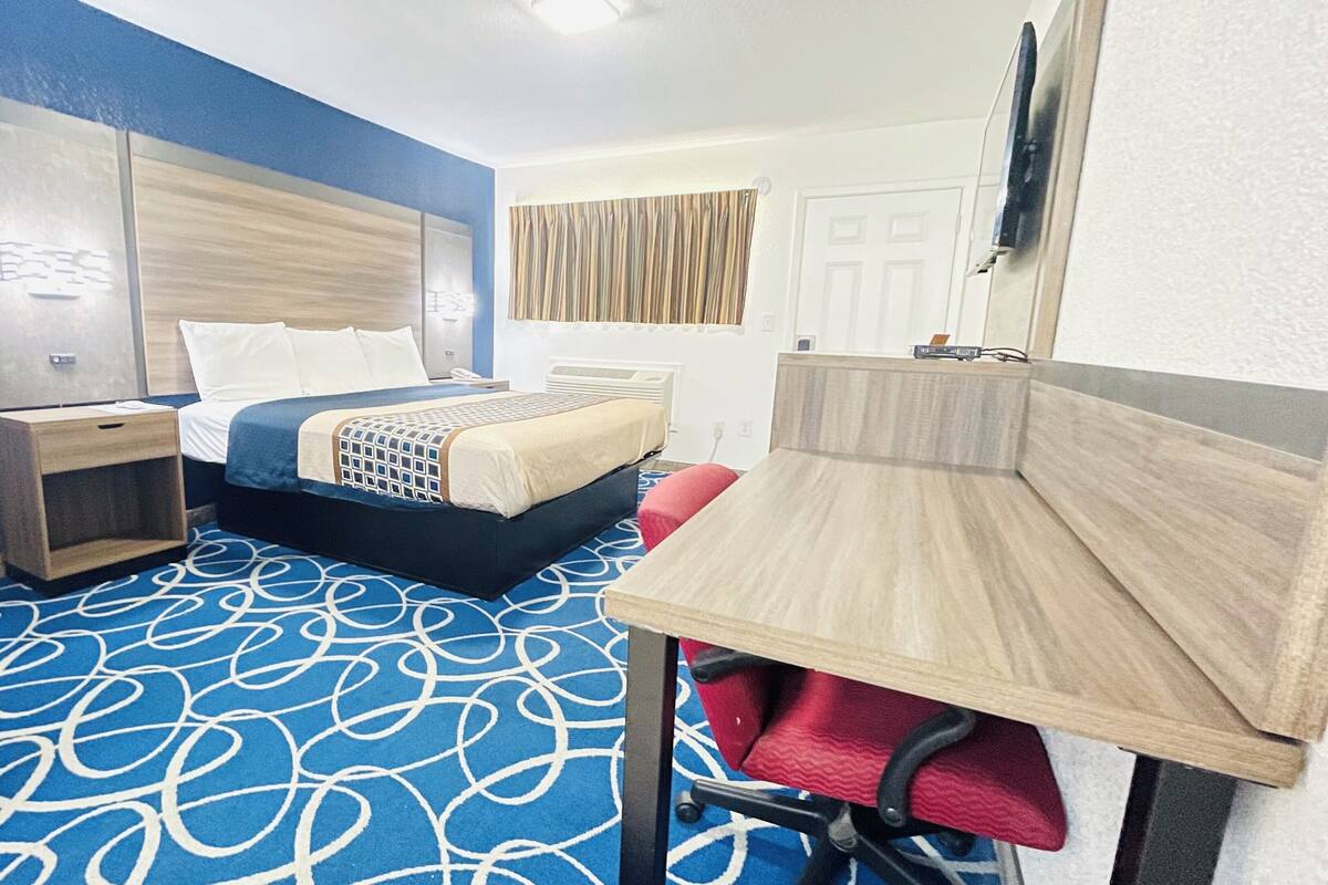 Una habitación de hotel con una cama, mesitas de noche, un escritorio y una silla.