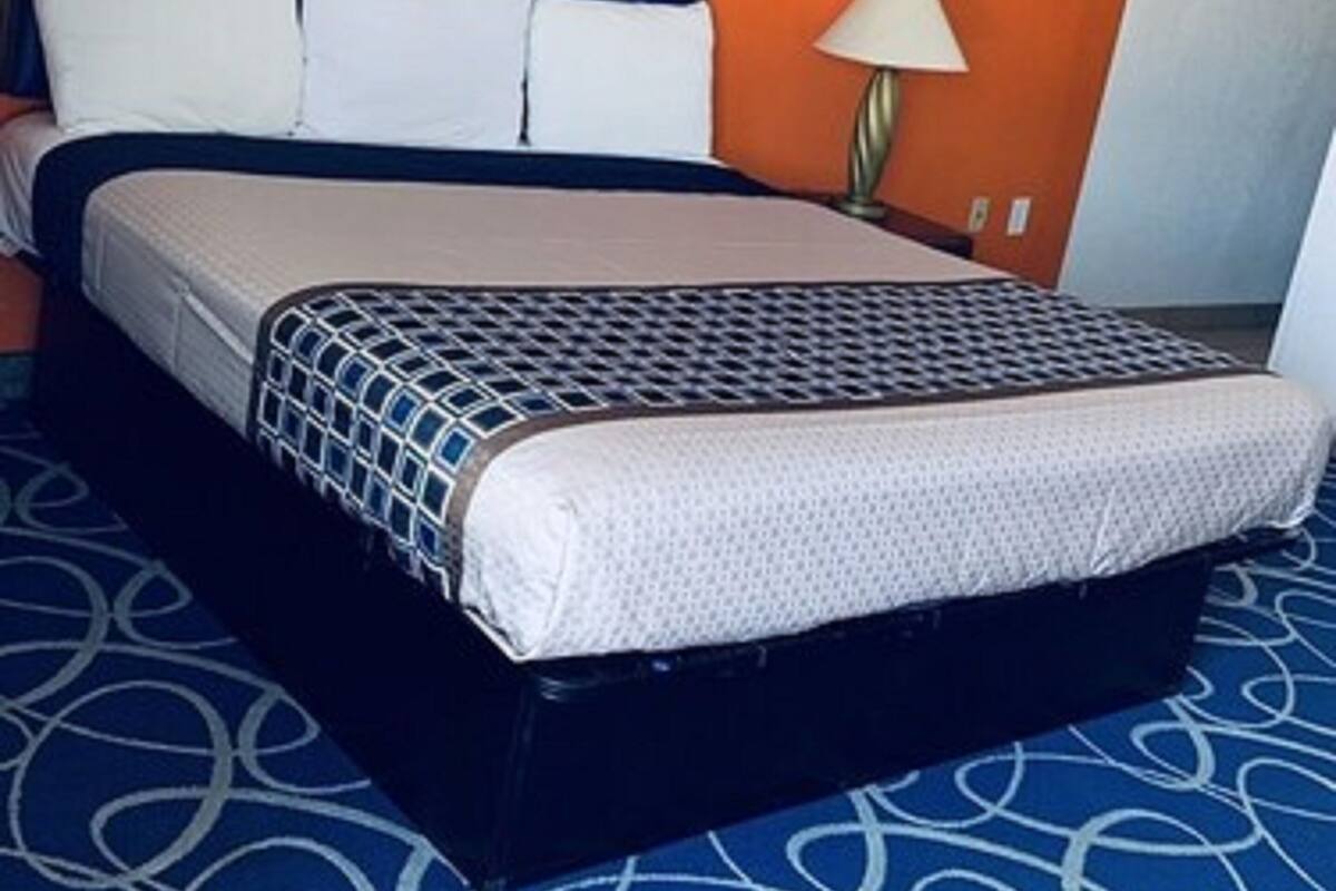 Una habitación de hotel con una cama, un cuadro en la pared y una lámpara.