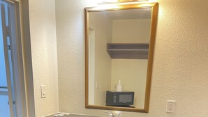 Une salle de bain avec deux éviers, un miroir et un four à micro-ondes.