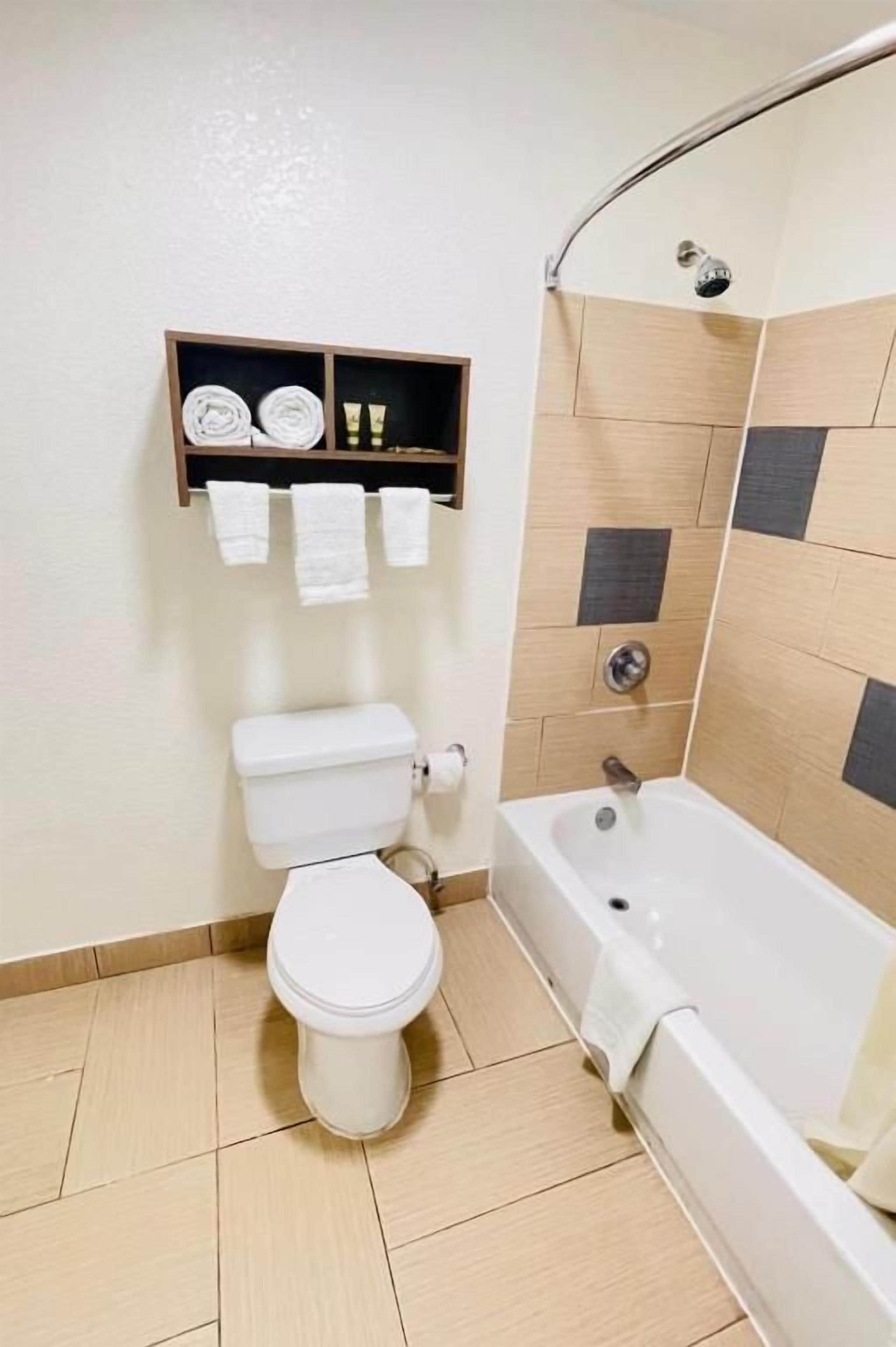 Un baño con inodoro, bañera y un estante con toallas.