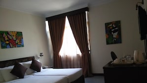 A hotel room with two beds, a desk with a telephone and a coffee maker, and a window with curtains. - GeoPark Hotel (Langkawi)