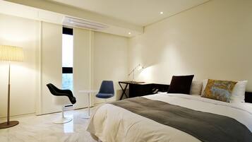 Una habitación de hotel moderna con una cama grande, un escritorio, una silla y una lámpara.