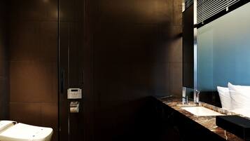 A modern bathroom with a dark tiled wall, a marble countertop, a sink, and a toilet.
