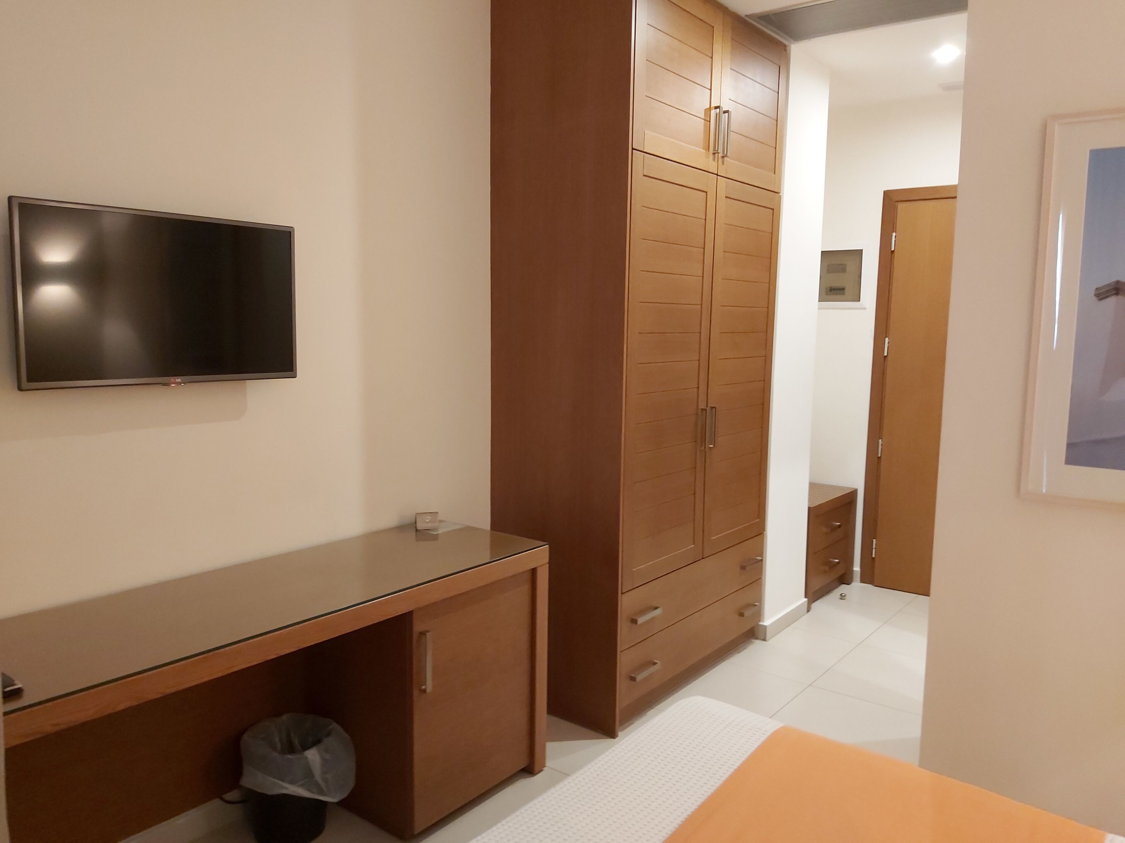 Ein Schlafzimmer mit Bett, Kleiderschrank, Schreibtisch und Fernseher.