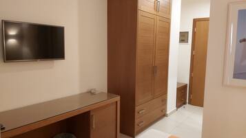 Ein Schlafzimmer mit Bett, Kleiderschrank, Schreibtisch und Fernseher.