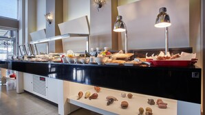 A buffet area with a variety of food items, a coffee station, and a display of nuts on the counter. - El Greco Hotel (Ierapetra)