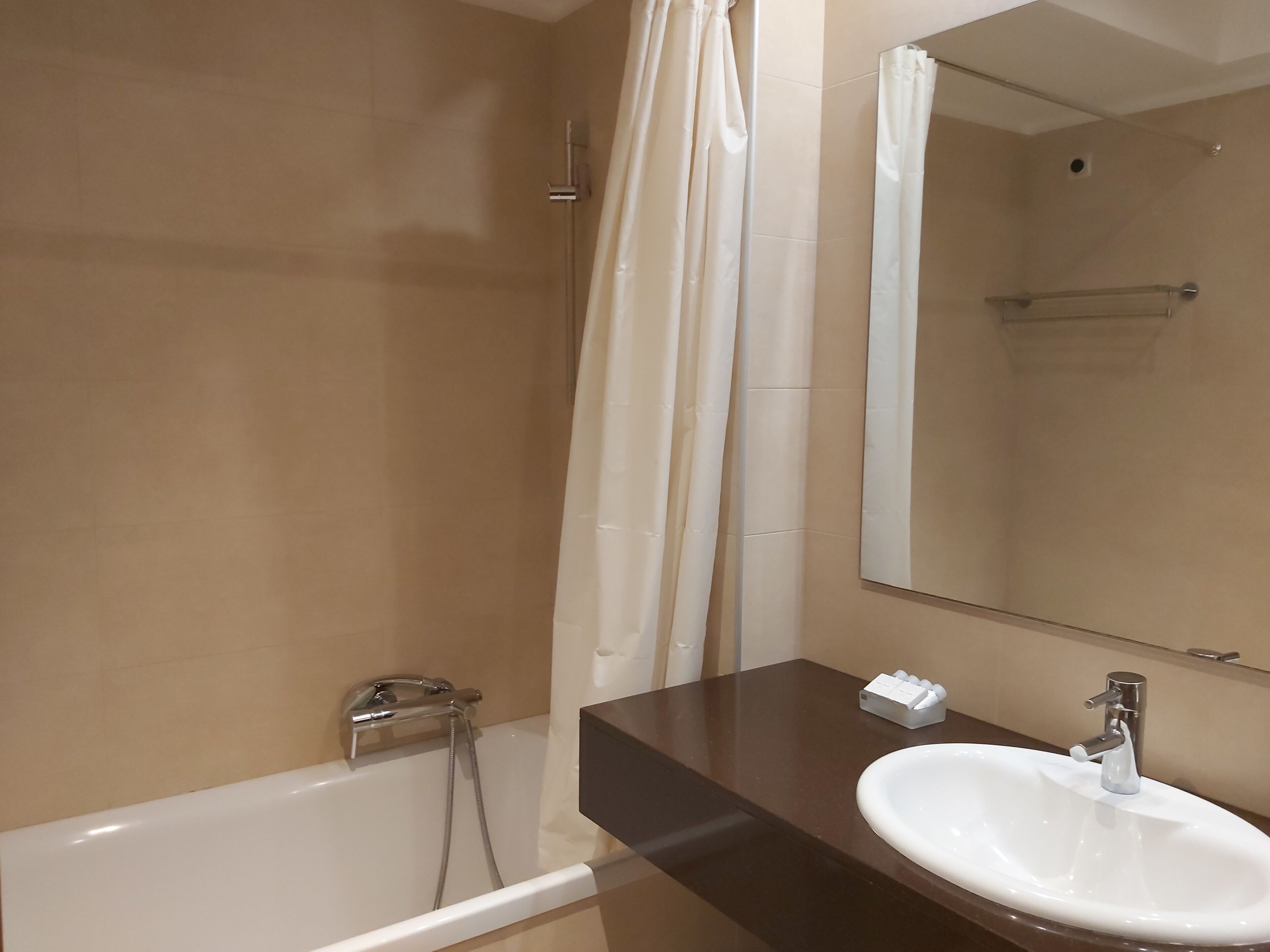 Un baño con bañera, lavabo, espejo y cortina de ducha.