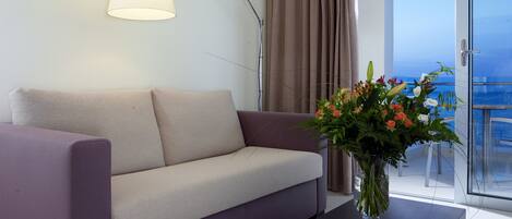 Una sala de estar moderna con un sofá, una mesa de centro, una lámpara y un jarrón con flores.