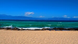 A beach with clear turquoise water, a sandy shore, and distant mountains under a blue sky. - El Greco Hotel (Ierapetra)