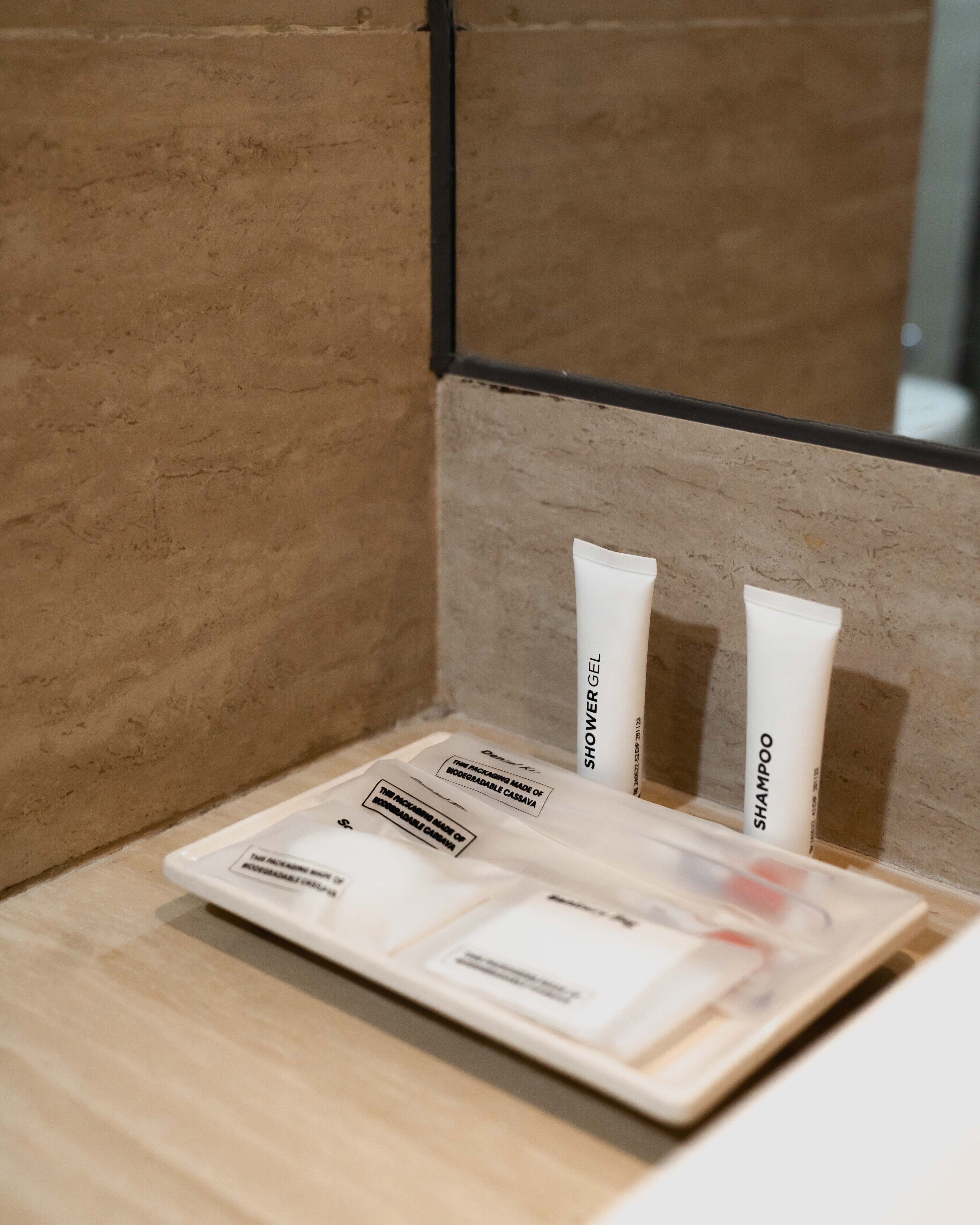 Un baño con tocador de madera, un espejo y artículos de aseo que incluyen gel de ducha y champú.