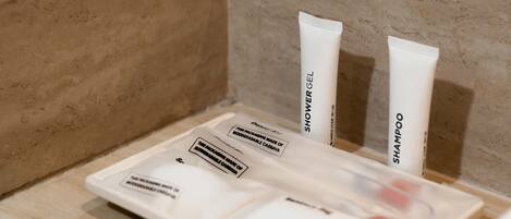 A bathroom with a wooden vanity, a mirror, and toiletries including a shower gel and shampoo.