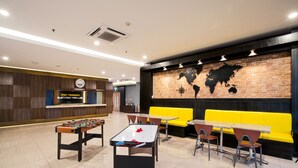 A modern indoor space with a foosball table, yellow seating, and a world map mural. - ROOMS INC d’botanica Bandung (Bandung)
