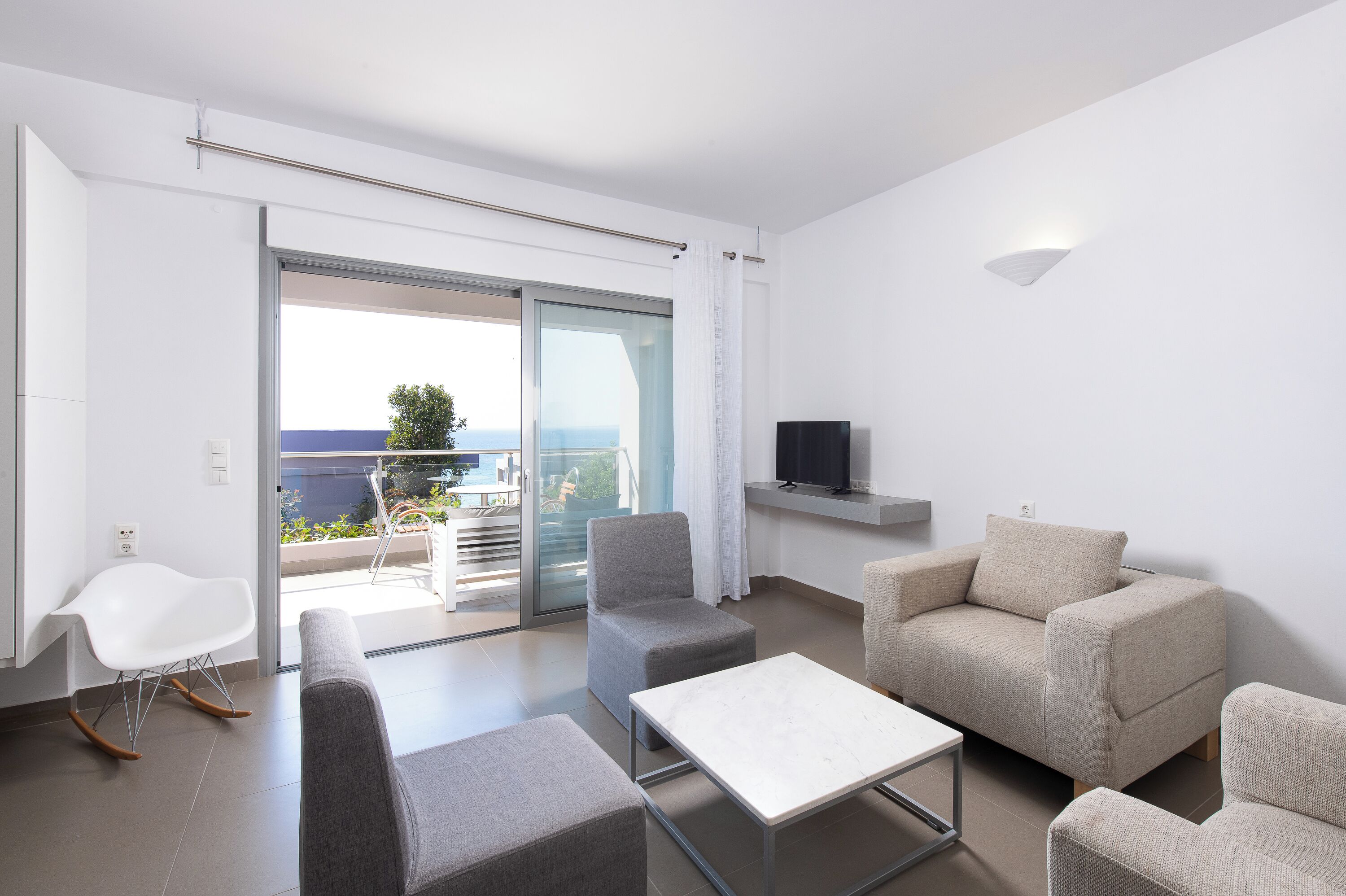 A modern living room with a sofa, armchairs, a coffee table, and a TV.