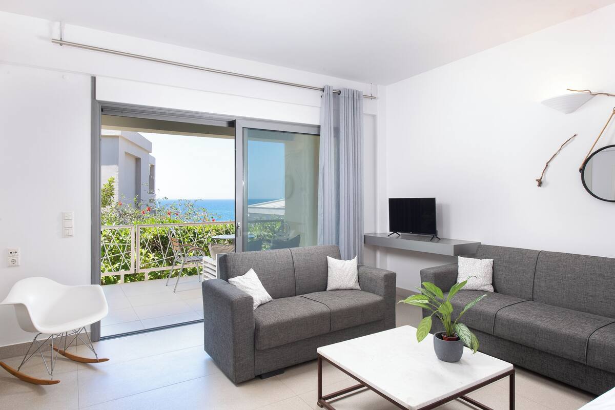 A modern living room with a grey sofa, a white coffee table, and a potted plant.