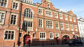 A red brick building with arched windows and a prominent red door.