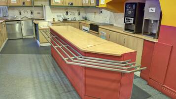 A modern kitchen with stainless steel appliances, a red bar counter, and a milk dispenser.