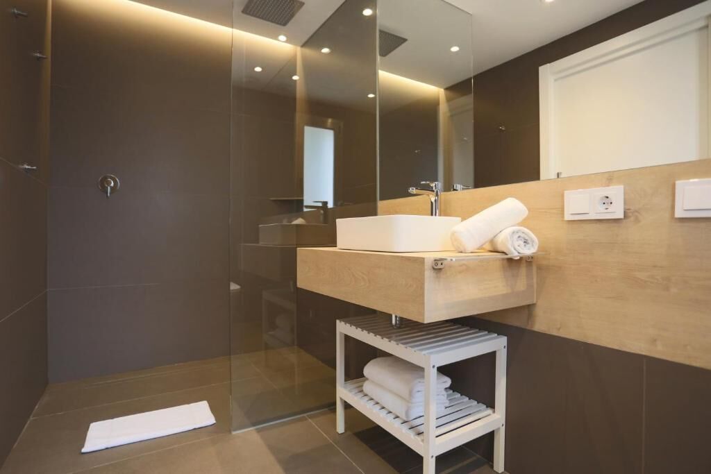 A modern bathroom with a glass-enclosed shower, a wooden vanity with a sink, and a towel rack.
